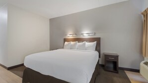 Una habitación de hotel con una cama grande, mesitas de noche e iluminación en la pared.
