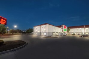 A hotel with a modern design, featuring multiple floors and a parking area with several cars. - Red Roof Inn San Antonio - Seaworld/ Northwest (San Antonio)