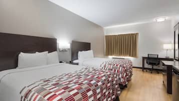 A hotel room with three beds, a desk, and a mirror.