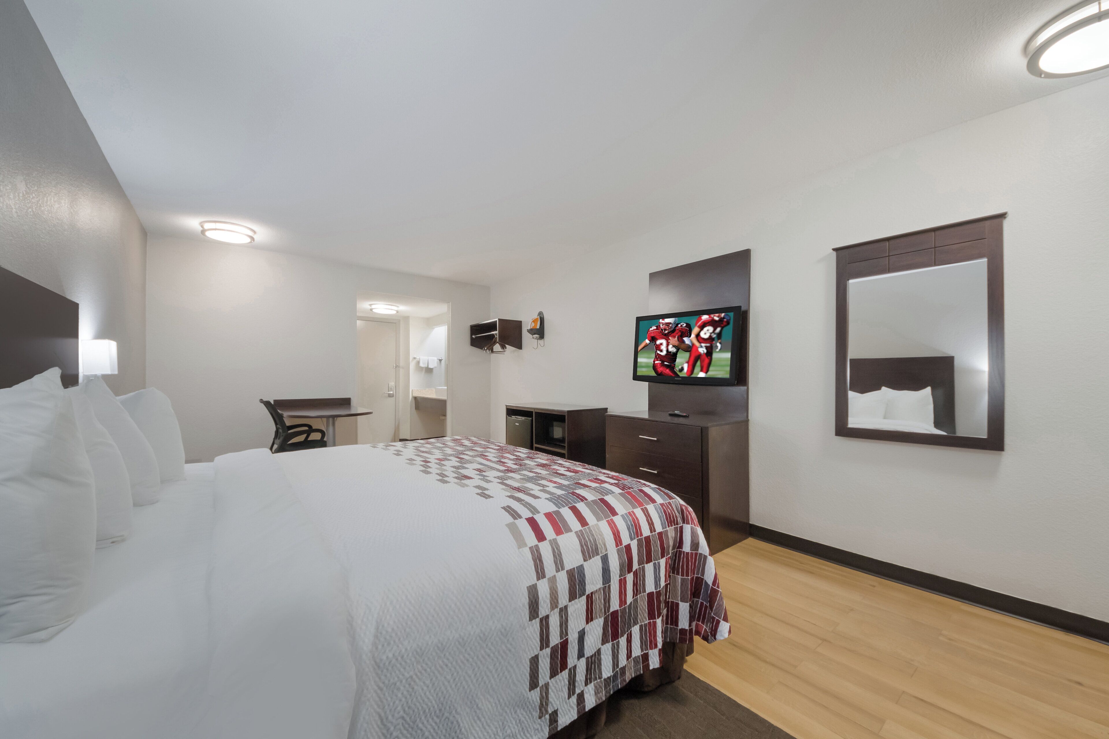 Una camera d'albergo con un letto, una scrivania, una televisione e uno specchio.