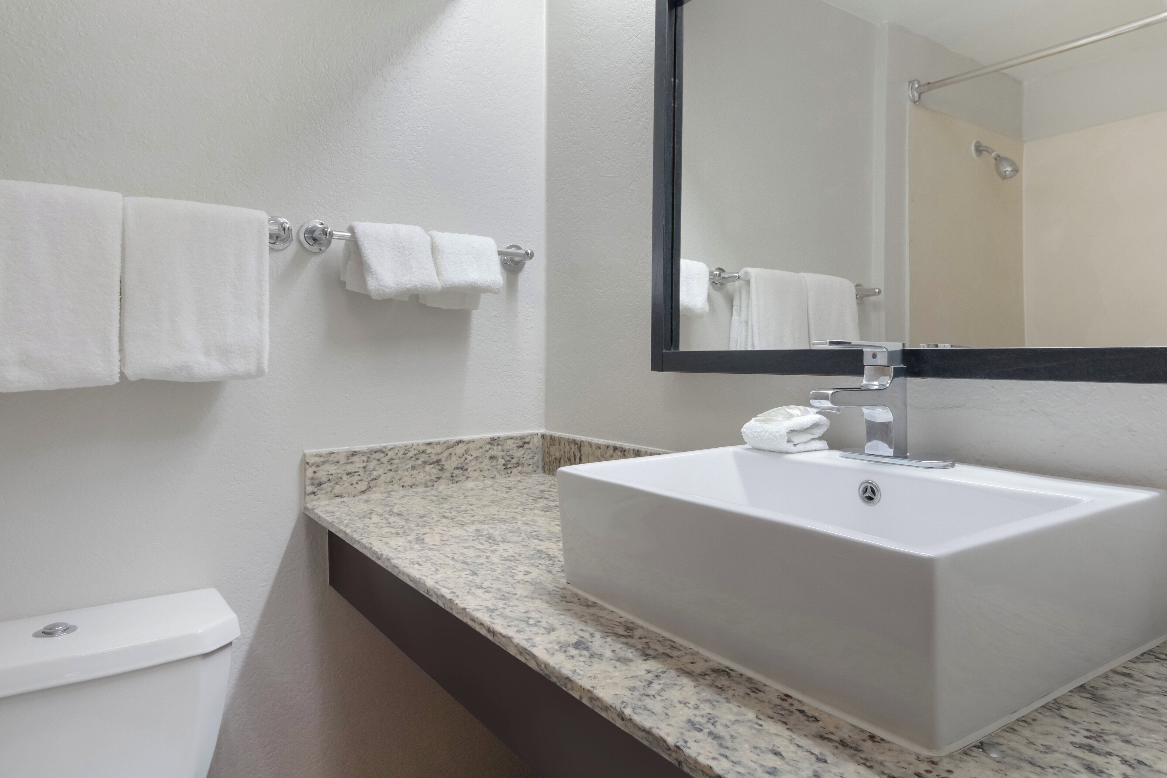 A bathroom with a white sink, a mirror, and two towel racks.