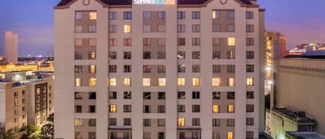 Un hotel Sonesta con varios pisos, un patio central y un paisaje urbano al fondo.
