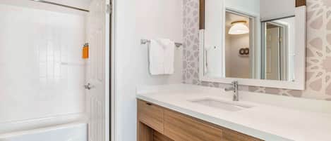 Un bagno moderno con vasca, uno specchio grande e un mobile lavabo.