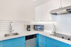A modern kitchen with white and blue cabinets, a dishwasher, a microwave, and a coffee maker.