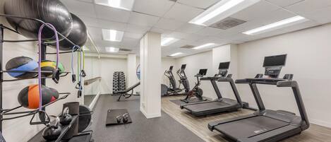 A gym with treadmills, exercise balls, and kettlebells.