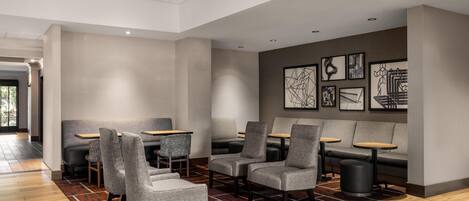 A modern interior with seating areas, tables, and artwork on the walls.