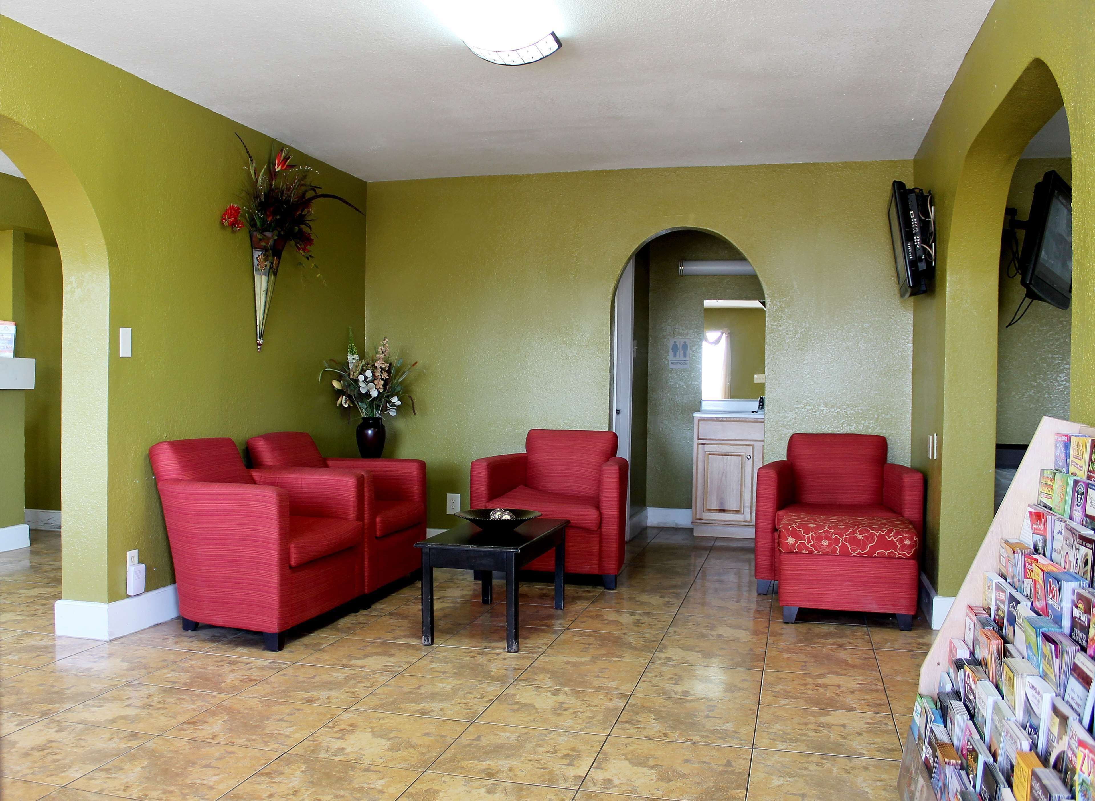 A living room with red sofas, a coffee table, and a bookshelf filled with books.