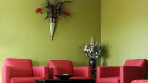 Ein Zimmer mit einer grünen Wand, zwei roten Sofas, einem schwarzen Tisch und einer Vase mit Blumen.