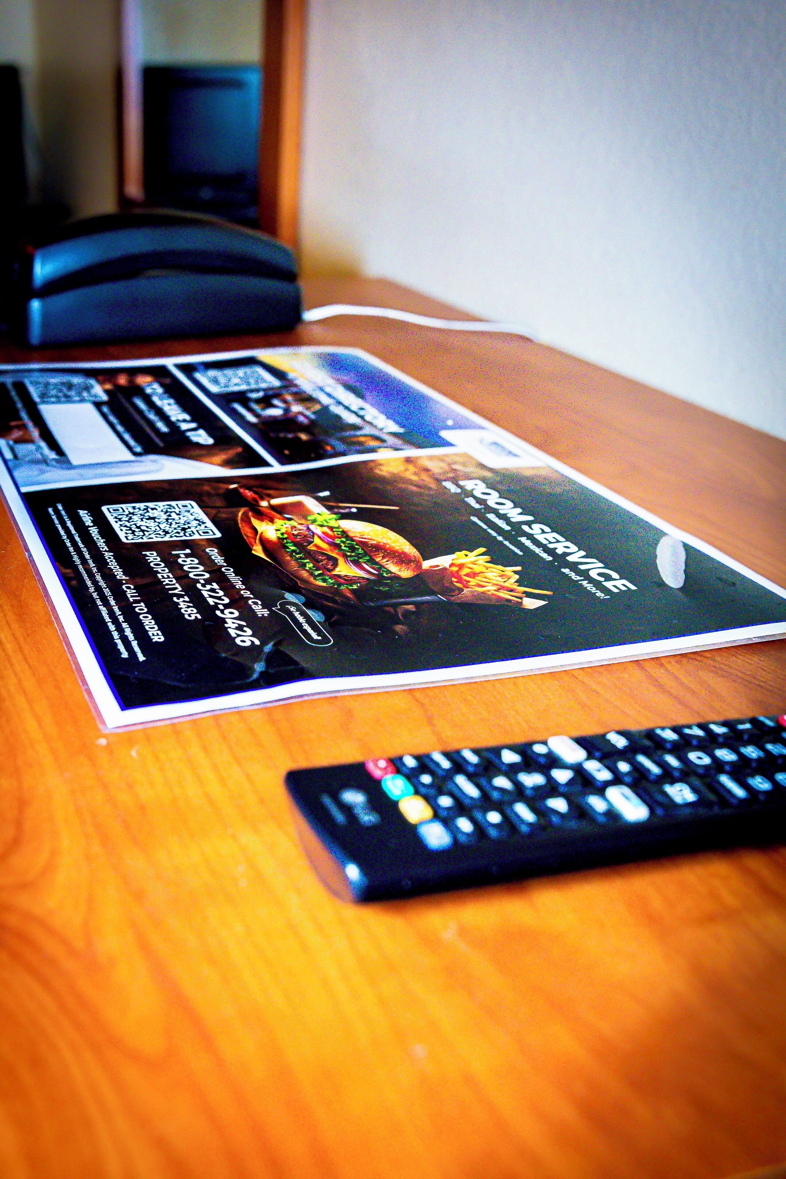 Een brochure op een houten tafel, met een afstandsbediening ervoor.