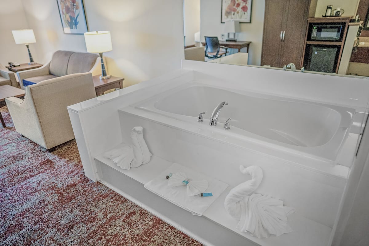 A modern bathroom with a large bathtub, two sinks, and a mirror.