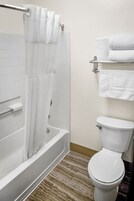Ein Badezimmer mit einer weißen Badewanne, einer Toilette und einem Handtuchhalter mit gefalteten Handtüchern.