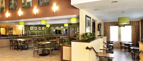 A spacious hotel lobby with multiple seating areas, a central counter, and artwork on the walls.