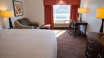 Habitación de hotel con una cama grande, un escritorio con una silla, una mesita y dos lámparas.