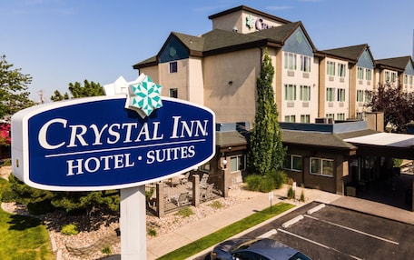 A sign for Crystal Inn Hotel Suites with a modern building in the background.