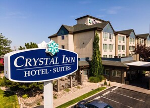 Un letrero de hotel con el nombre 'Crystal Inn Hotel Suites' y un edificio al fondo.