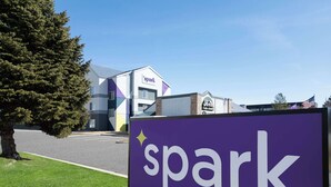 A 'spark by Hilton' sign in front of a building with a modern design, featuring a mix of geometric shapes and a prominent American flag. - Spark by Hilton Salt Lake City Airport (Salt Lake City)
