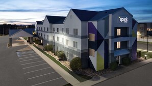 A modern hotel with a geometric facade, multiple entry points, and a parking lot. - Spark by Hilton Salt Lake City Airport (Salt Lake City)