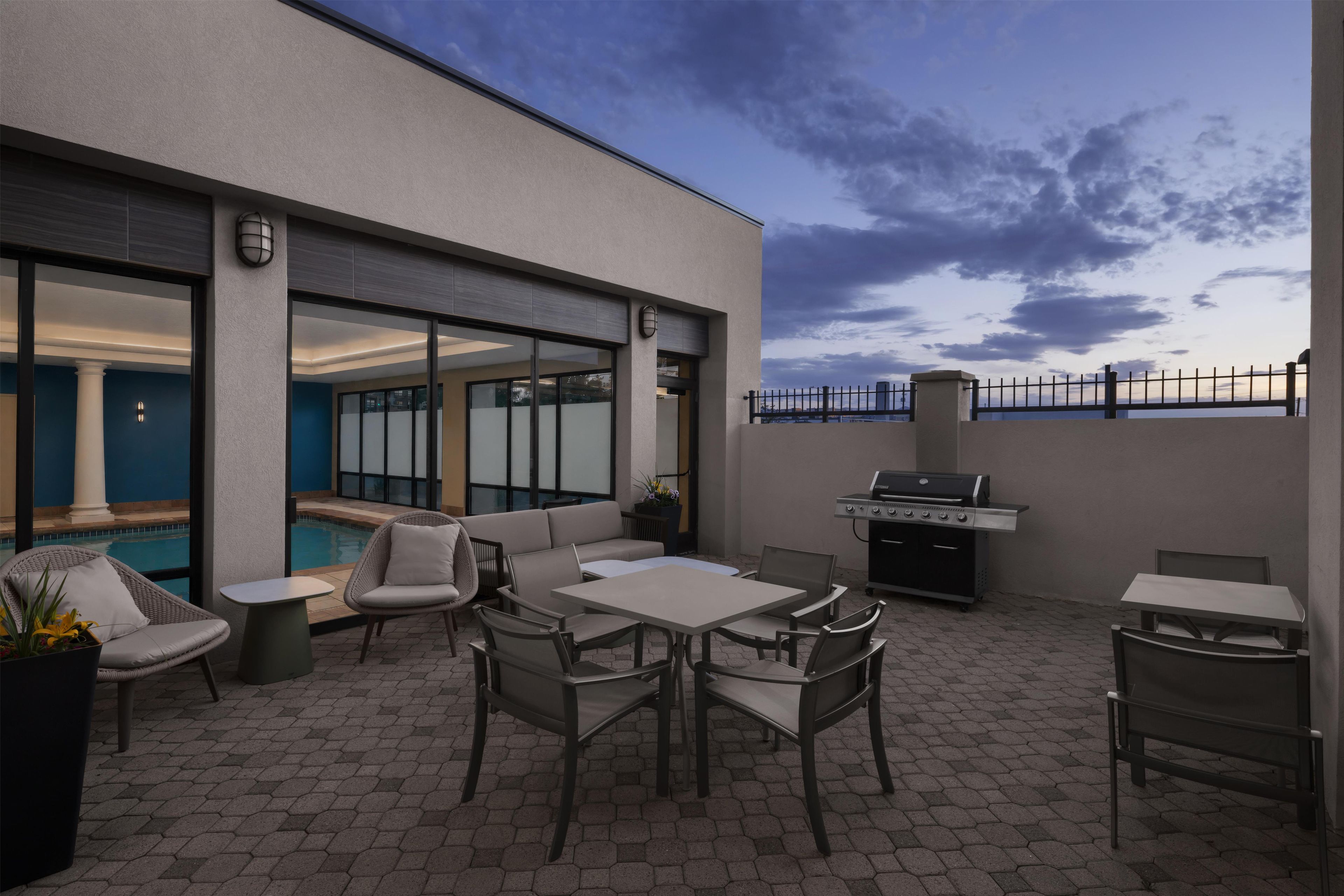 Um pátio externo com assentos, churrasqueira e vista para a piscina.