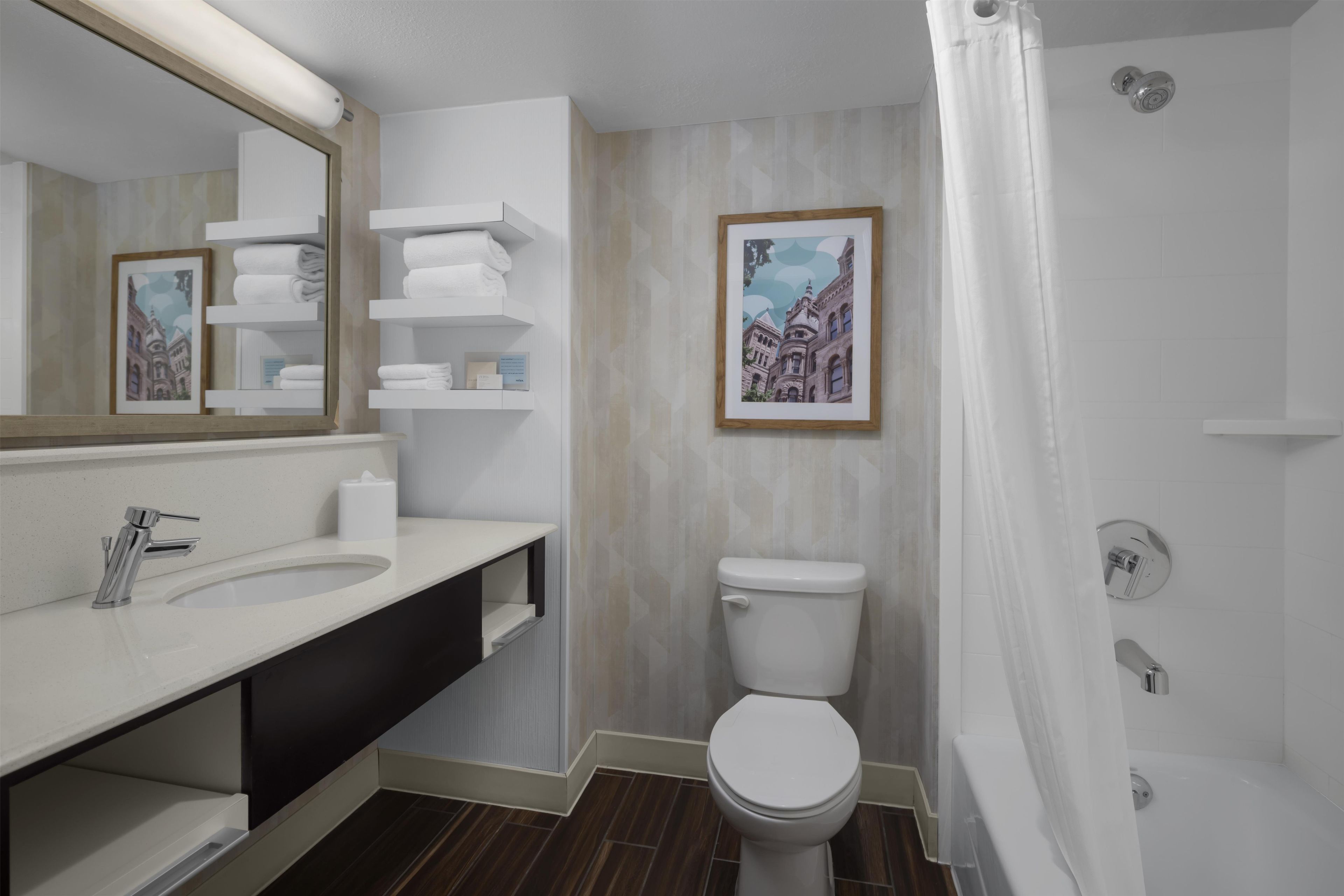 Baño con lavamanos blanco, espejo, inodoro y cortina de ducha.