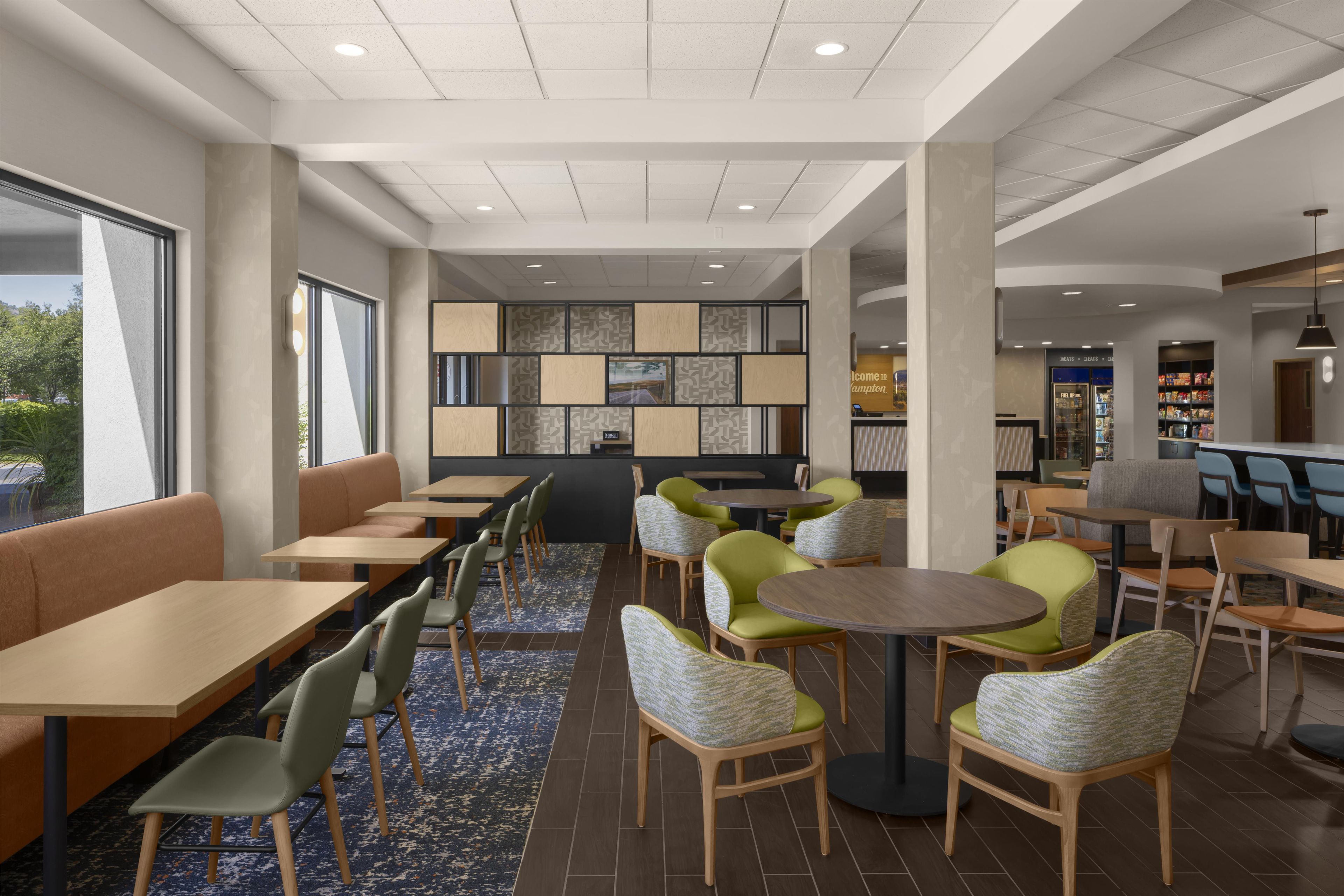 A modern indoor seating area with tables and chairs, a patterned wall, and a reception desk.
