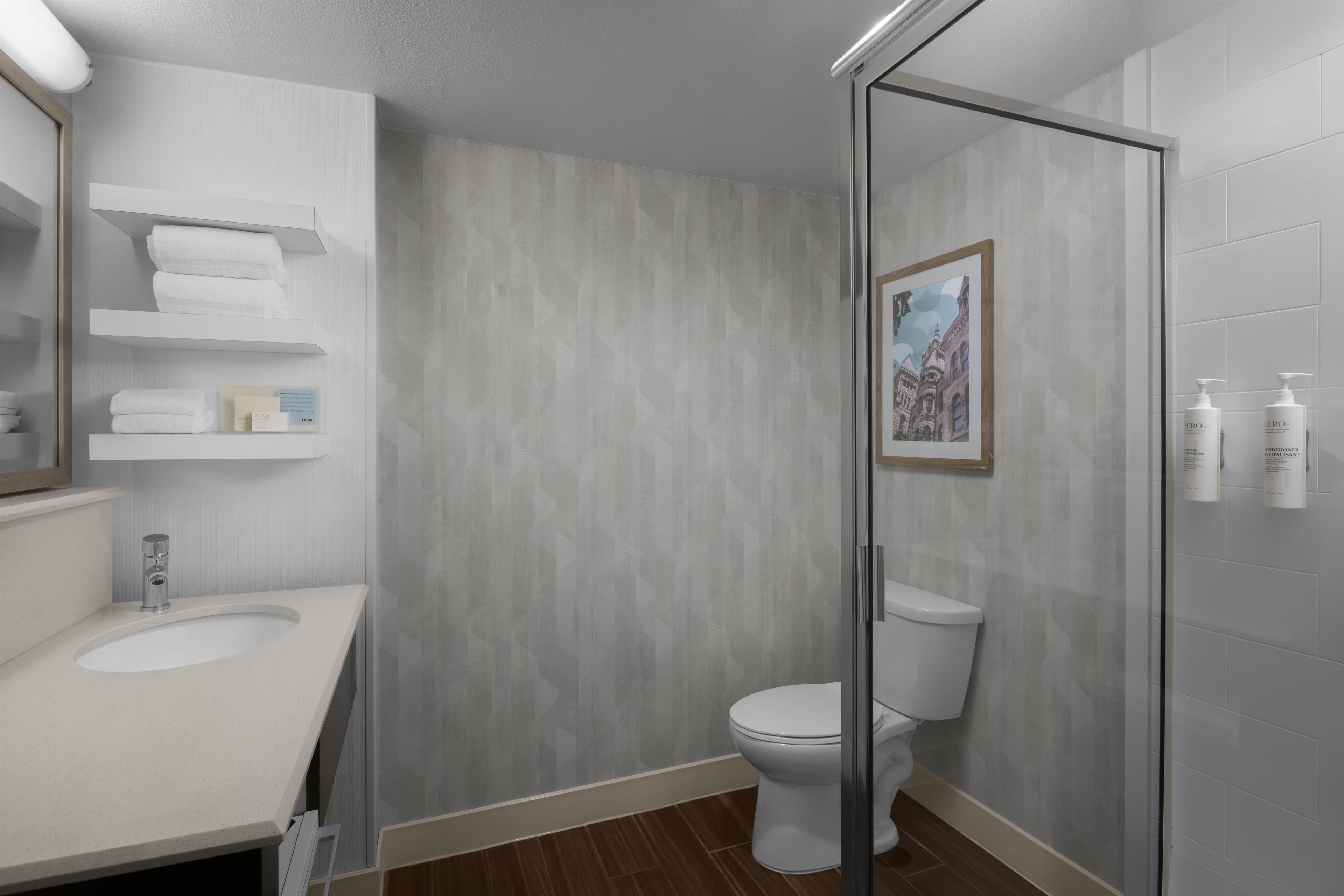 A modern bathroom with a glass shower enclosure, a white toilet, and a vanity with a sink.