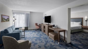 Une chambre d’hôtel équipée d’un canapé, d’un bureau, d’une télévision, d’un lit et d’une chaise.