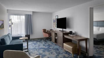 A hotel room with a bed, a desk, a television, a sofa, and a chair.