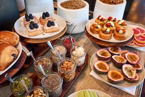 A variety of pastries and desserts on a wooden table, including blackberries, figs, and nuts in jars. - Hotel SLC (Salt Lake City)