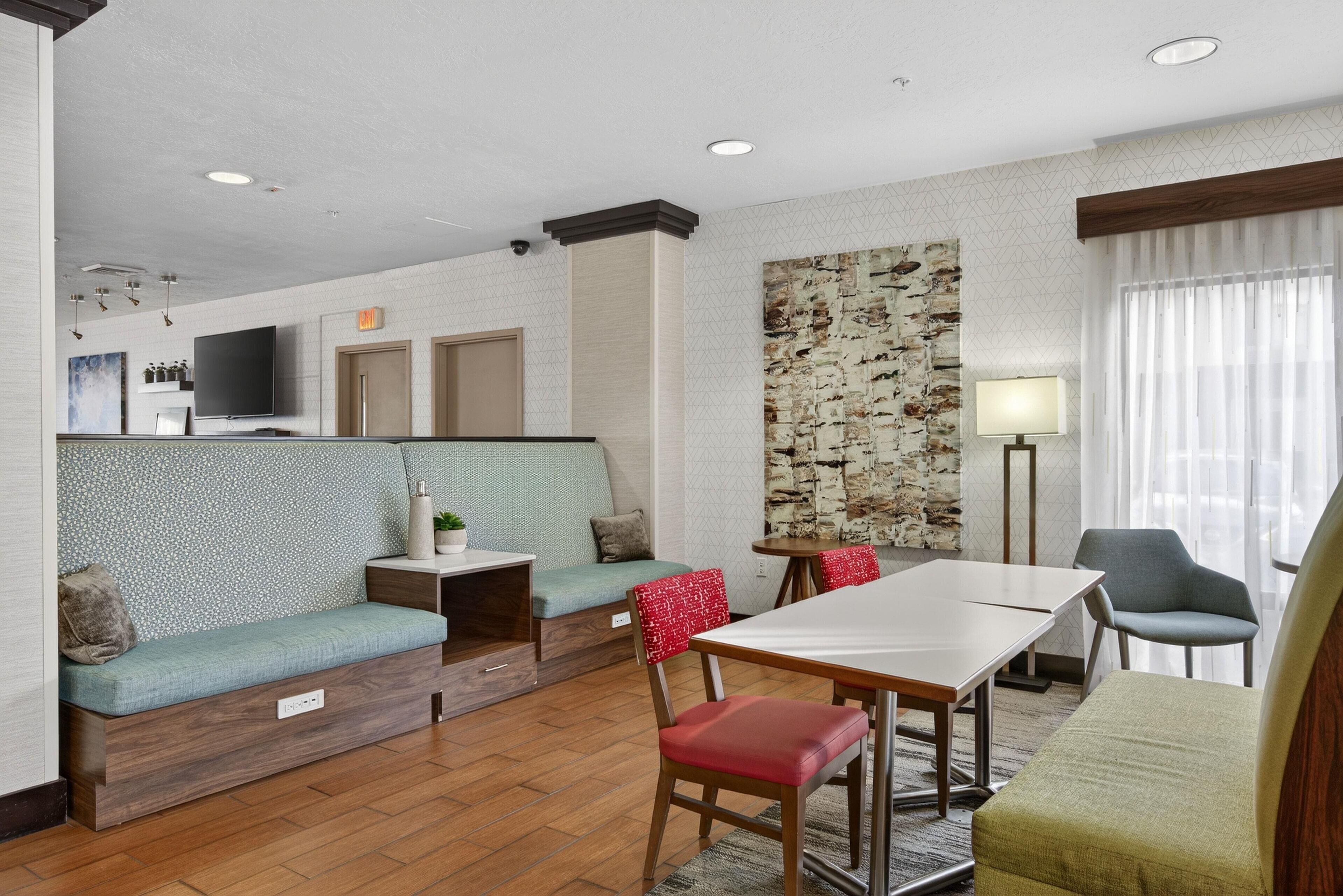 Une chambre d’hôtel moderne avec un coin repas, un canapé et une télévision.