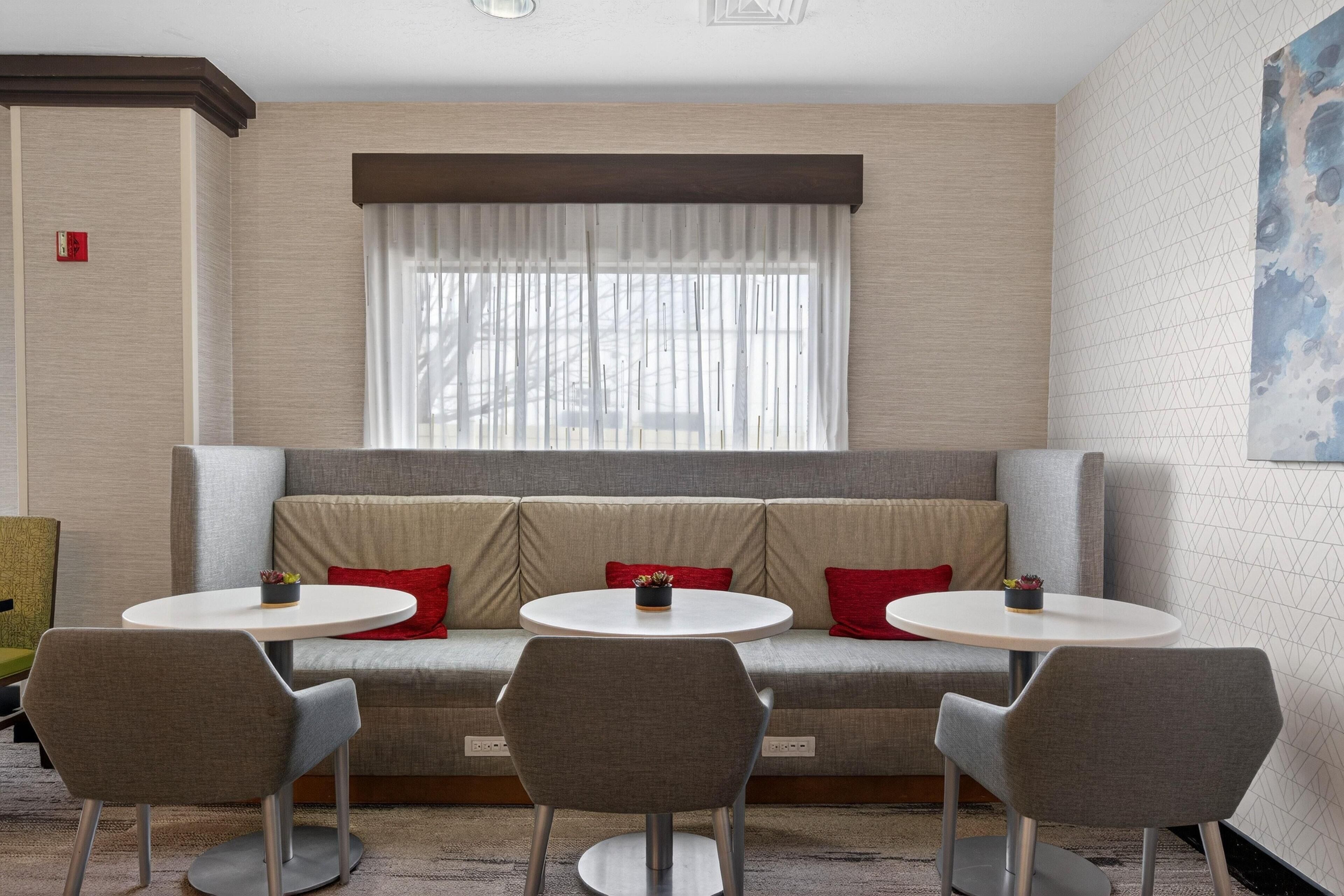 A modern room with a sofa, two round tables, and three chairs.