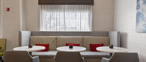 A modern room with a sofa, two round tables, and three chairs.