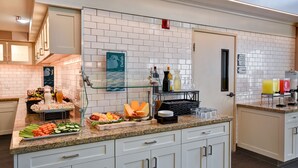 Un buffet proposant une variété de plats et de boissons, une vitrine réfrigérée et un panneau indiquant l’emplacement du buffet.