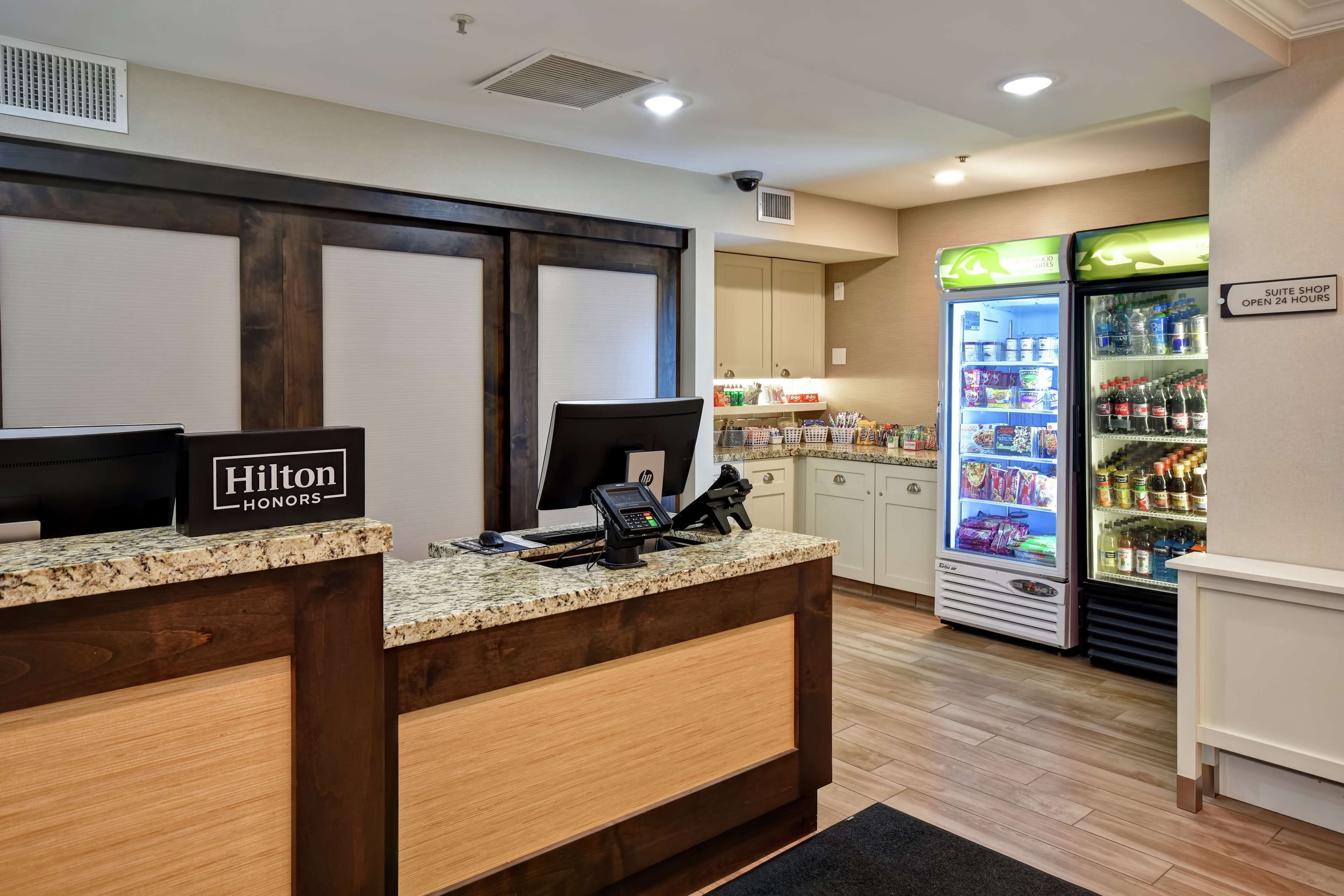 A hotel reception area with a counter, a computer, a phone, and a minibar.