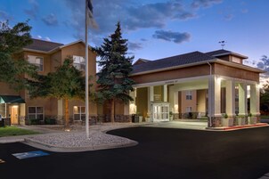 Un hotel con entrada despejada, asta de bandera e iluminada entrada de vehículos.