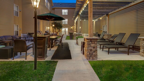 Un espace extérieur aménagé en patio, avec des sièges, une table et un lampadaire.