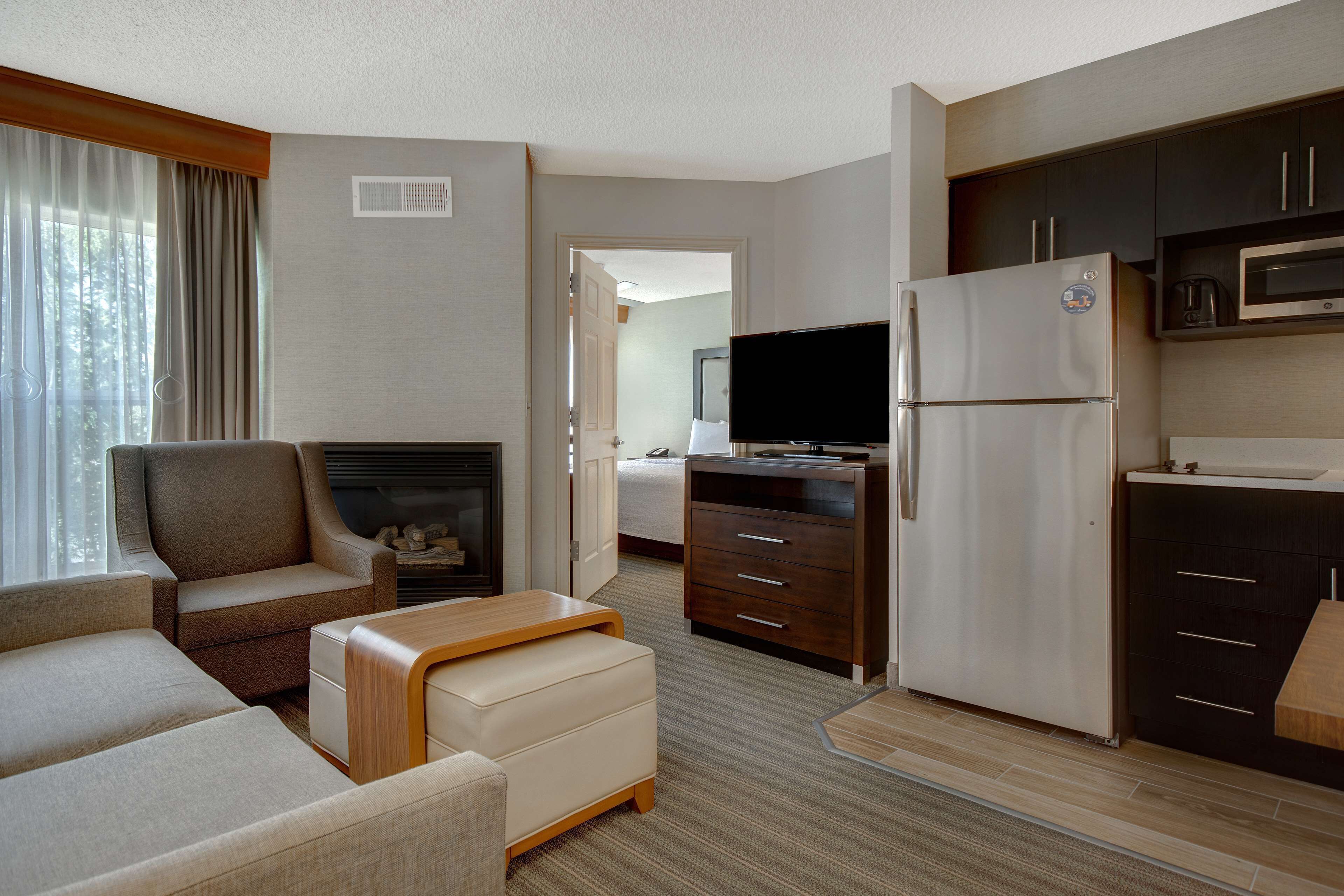 Habitación de hotel con sala de estar, kitchenette y televisor.