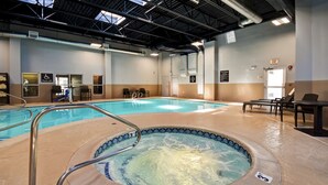 Une piscine intérieure dotée d’un jacuzzi, de chaises longues et d’un dispositif d’élévation pour faciliter l’accès à la piscine.