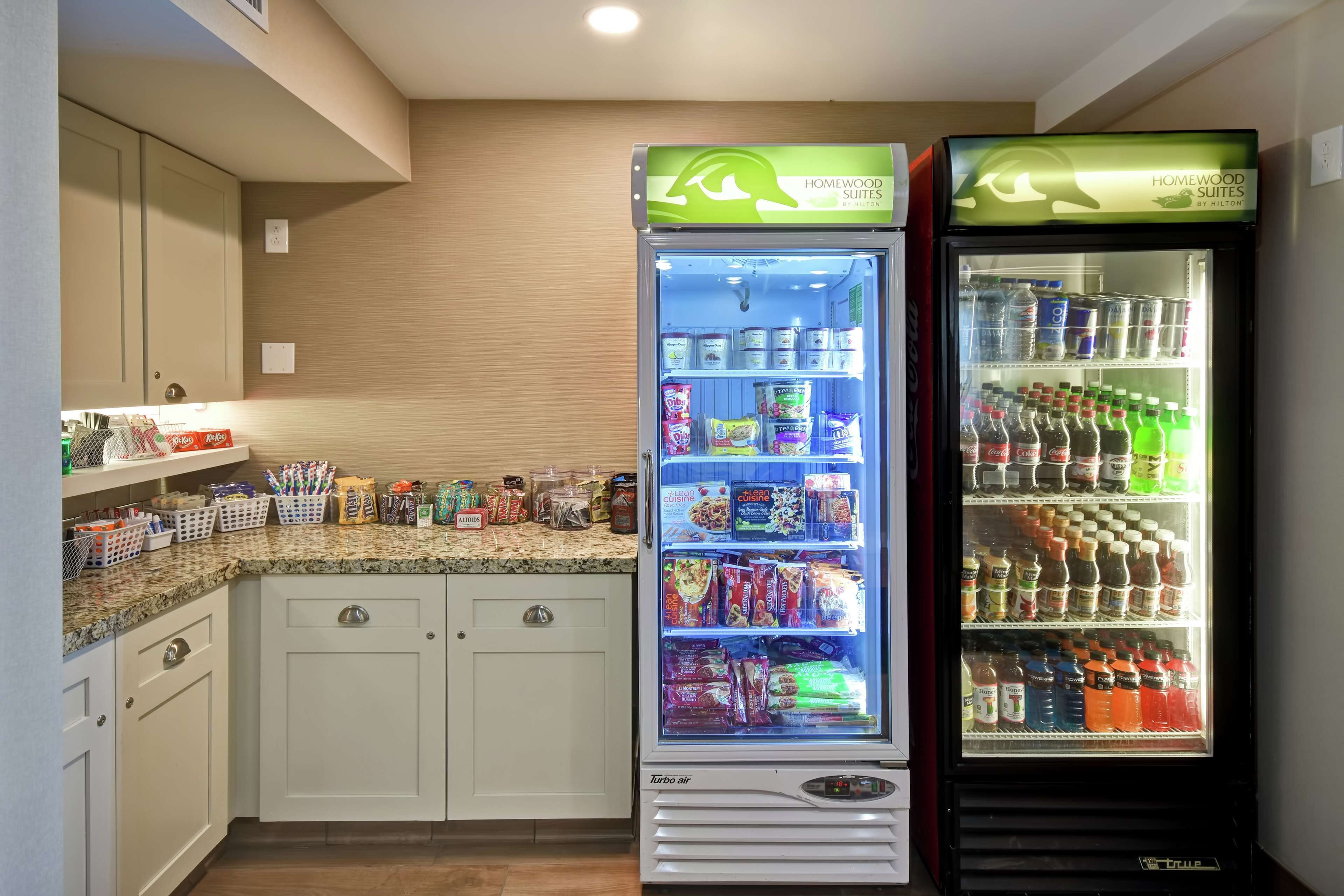 Een kitchenette met twee drankdispensers, waarvan er één gelabeld is met 