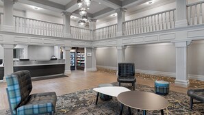 A spacious lobby with a reception desk, seating area, and a staircase.