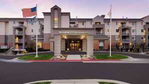 A multi-story hotel entrance with a central entrance, flagpoles, and a well-maintained lawn area.