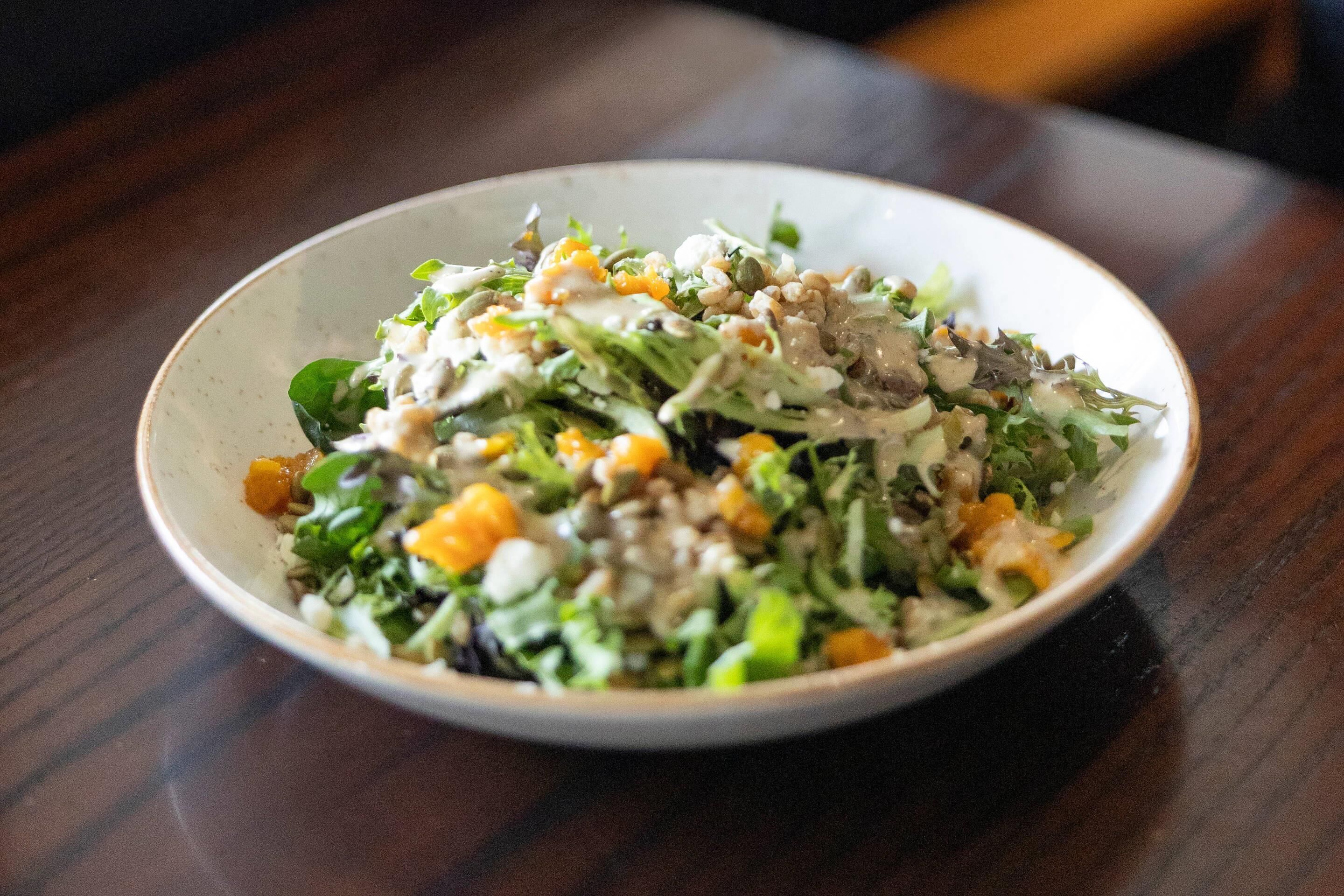 A bowl of salad on a wooden table.