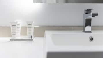 Un baño con un lavamanos blanco, un grifo de cromo y dos tubos de gel de ducha Radisson sobre una bandeja blanca.