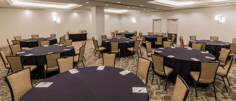 A conference room with multiple round tables and chairs, equipped with nameplates and pens.