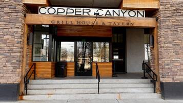 La entrada a Copper Canyon Grill House & Tavern, con fachada de ladrillo y detalles de madera.