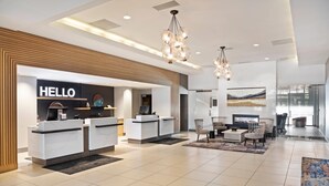 A modern hotel reception area with a 'HELLO' sign, a reception desk, seating area, and a fireplace. - Radisson Hotel Salt Lake City Downtown (Salt Lake City)