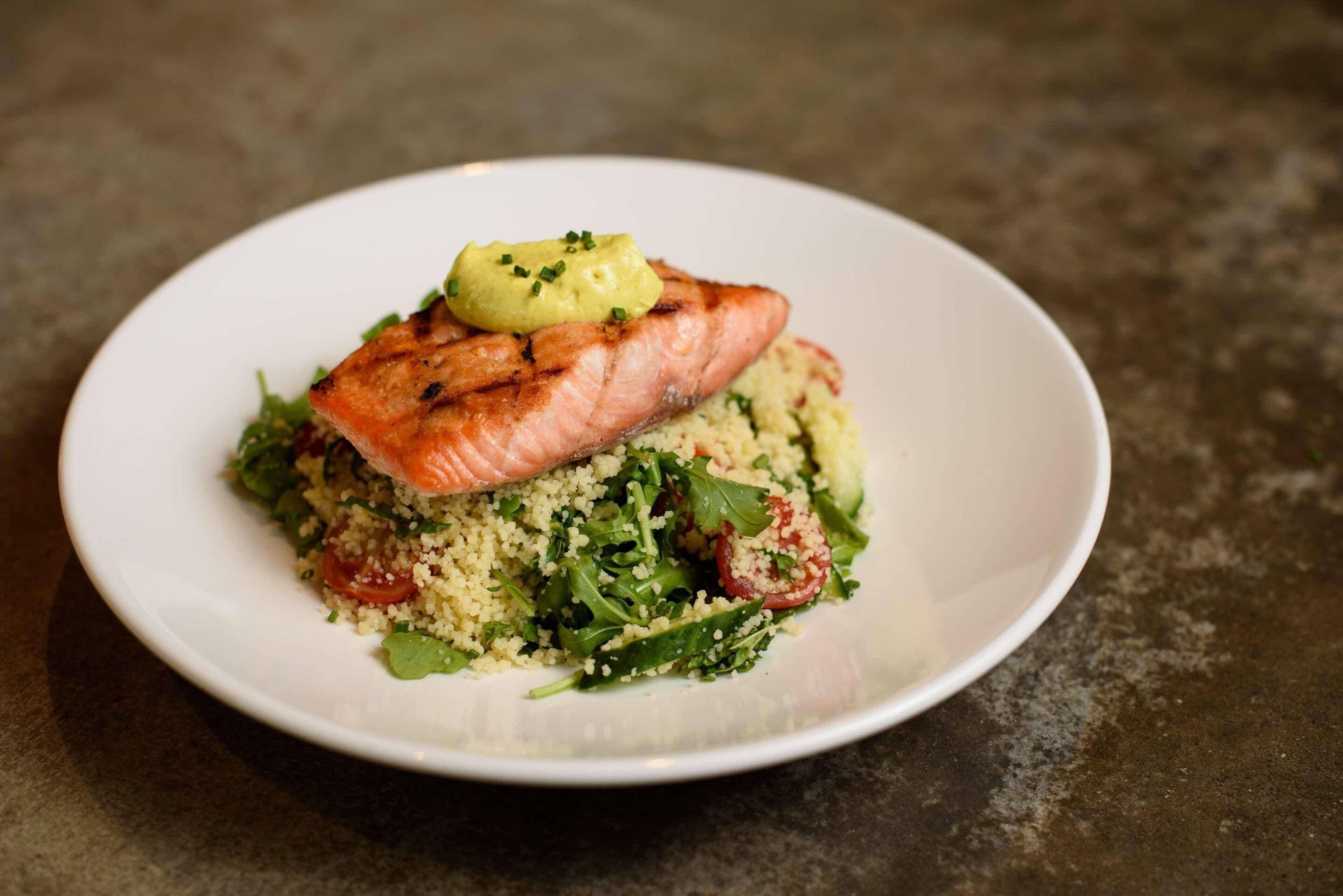 A plate with grilled salmon, couscous, and a green salad.