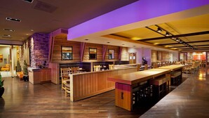 A restaurant with a long wooden bar, booths, and a stone accent wall. - Radisson Hotel Salt Lake City Downtown (Salt Lake City)