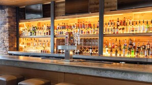 A bar with multiple shelves of liquor bottles, a tap system, and bar stools. - Radisson Hotel Salt Lake City Downtown (Salt Lake City)