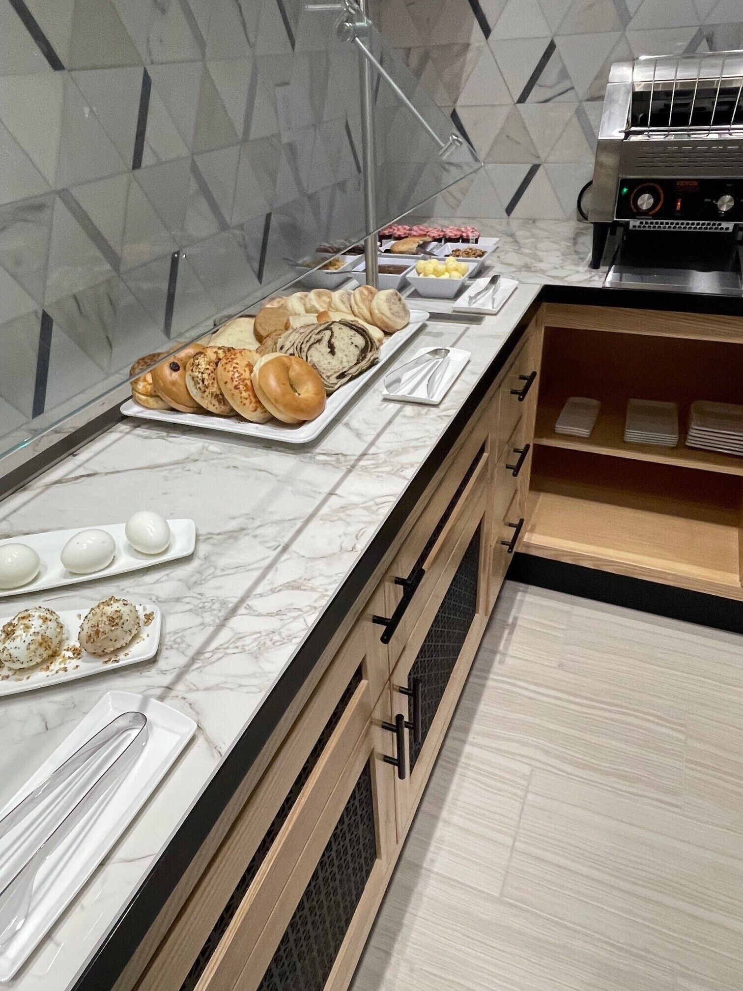 A buffet setup with various baked goods, a toaster, and a marble countertop.