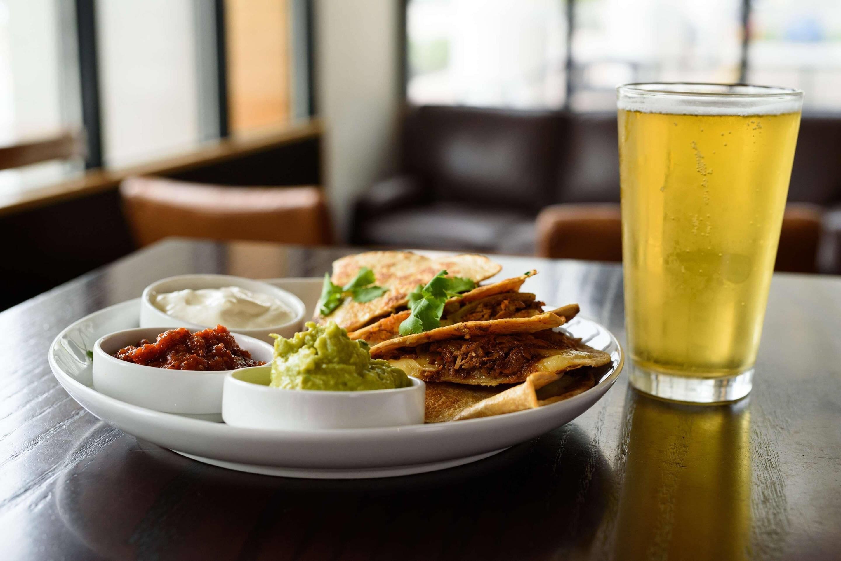 A plate with food and a glass of beer on a table.